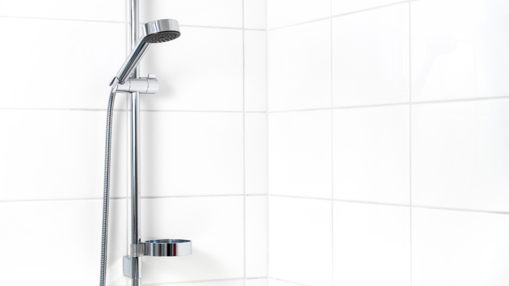 Shower hose on the wall of a bathroom with white tiles