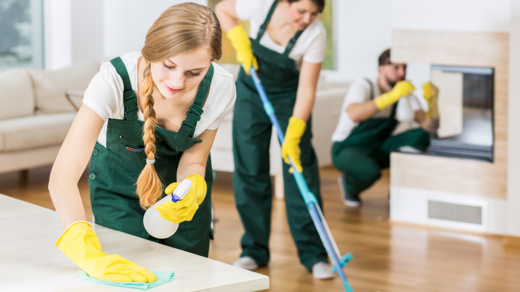 Cleaning lady wiping a countertop while two other cleaners working in the background.