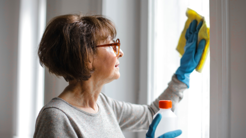 A lady wiping a clean cloth on the window