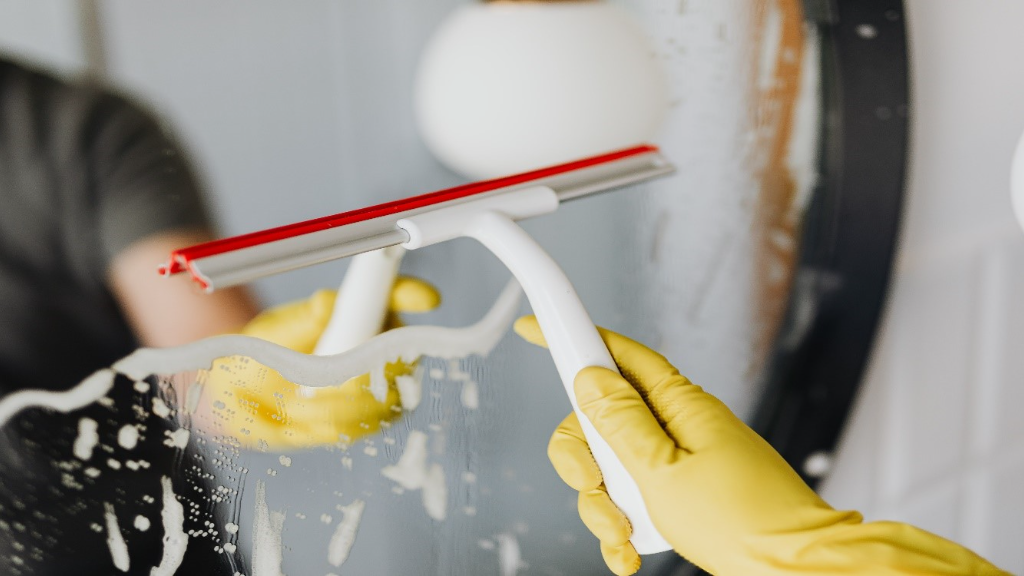 Person drying mirror with squeegee