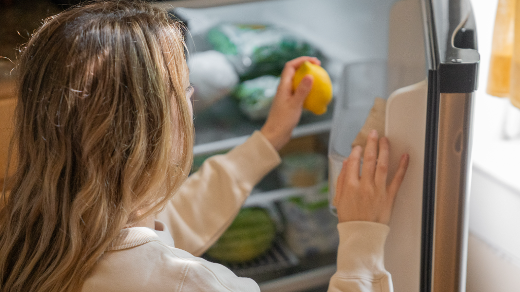 Woman taking lemon from refrigerator